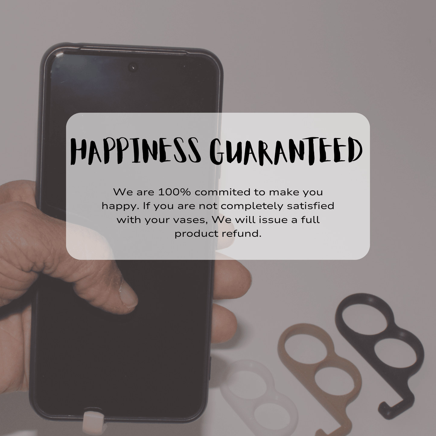 Hand holding a smartphone with a 'Happiness Guaranteed' text overlay on a blurred background.