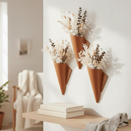 Decorative terracotta cone vases with dried plants on a wall in a home setting.