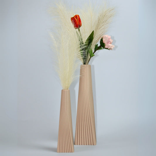 Two beige vases with ribbed texture holding dried plants and flowers on a light gray background