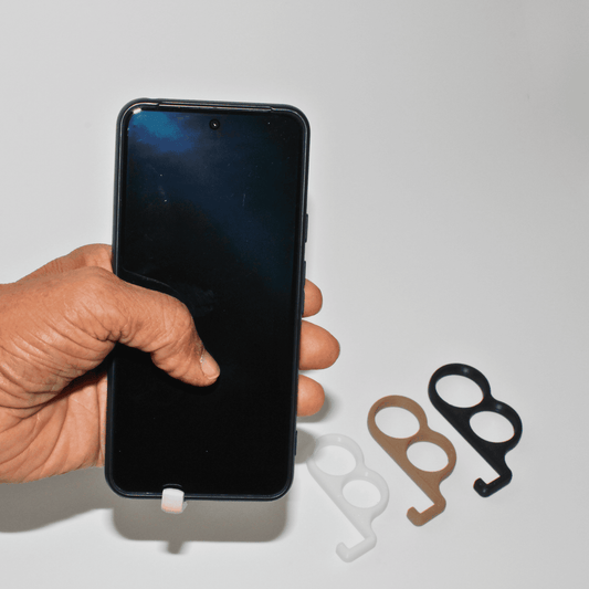 Hand holding a smartphone with two metal phone stands on a light gray background